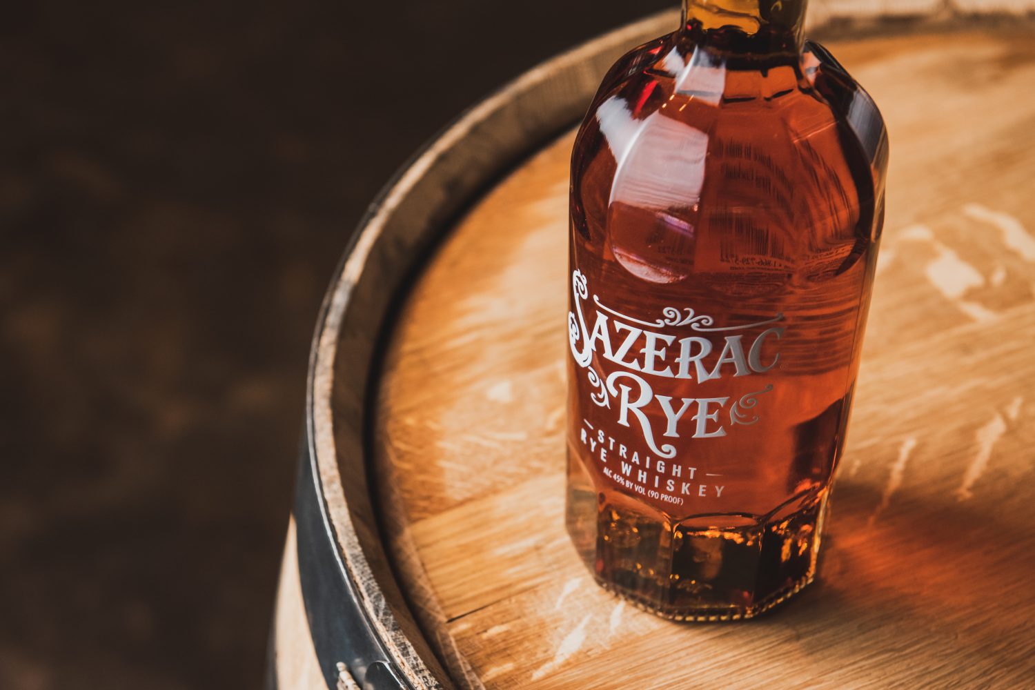 Bottle of Sazerac Rye sitting on top of a whiskey barrel.